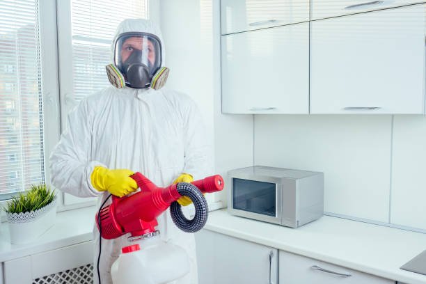 pest control worker standing with sprayer in kitchen .